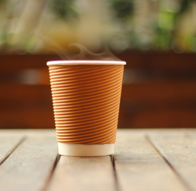 A steaming cup of coffee in a disposable cup. The Day center provides coffee and snacks to people who are homeless